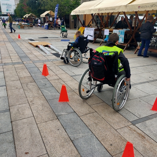 Dva učenca se preizkušata v vožnji z invalidskima vozičkoma na oviratlonu